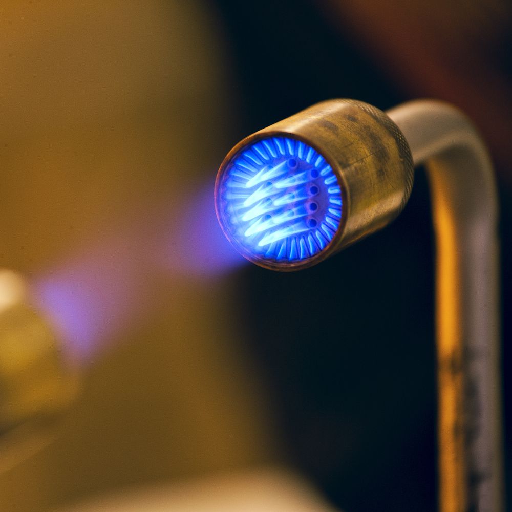 Brennende Gasflamme mit leuchtend blauem Feuer in metallischer Düse